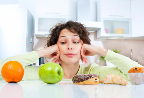Woman choosing between an apple and a cupcake