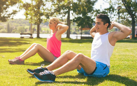 Man and woman doing sit-ups in a park