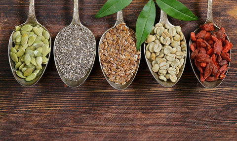 Pumpkin seeds, chia seeds, grains and goji berries in wooden spoons